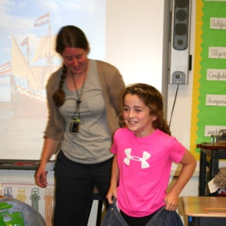 Carolyn Niehaus from the New Netherland Museum helps fourth-grader Lucie Curran try on slops, which were part of the traditional garb worn by sailors aboard Henry Hudsons ship, the &quot;Half Moon.&quot;