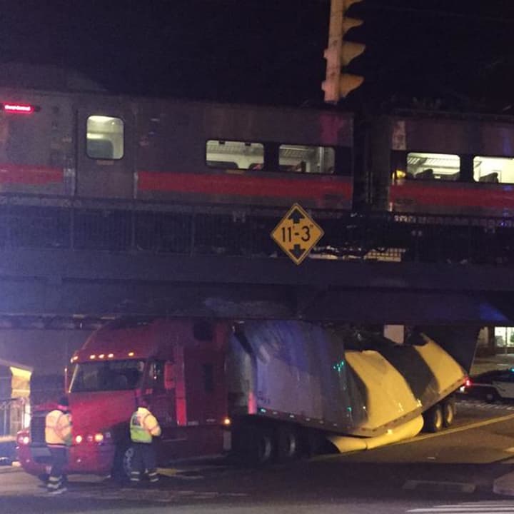 A tractor-trailer is wedged under a Metro-North train bridge in the center of Darien on Sunday night. 