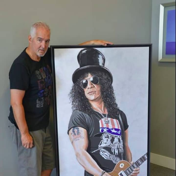 Michael Wagner standing beside his work &quot;Saul,&quot; a painting of Guns &#x27;N Roses guitarist Slash.