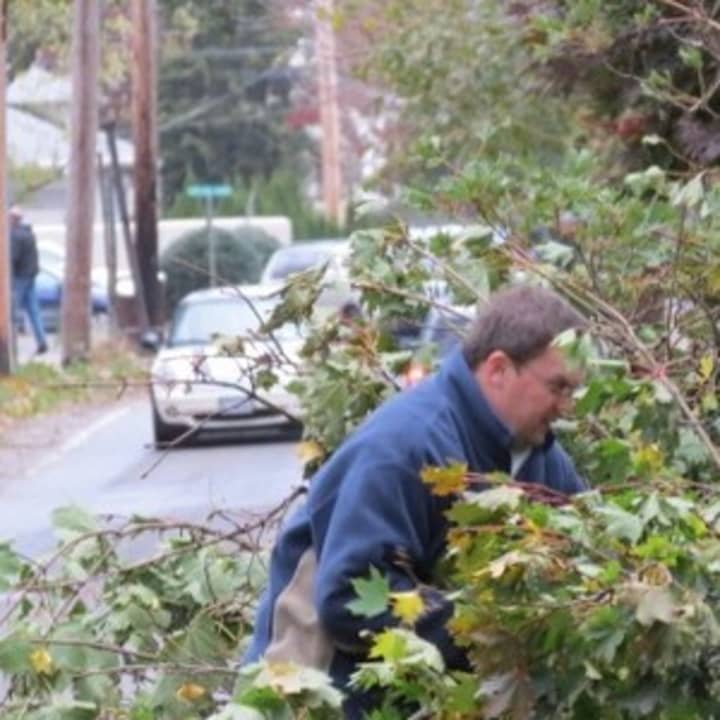 A resident clearing branches from a tree that fell on his lawn during Hurricane Sandy. 