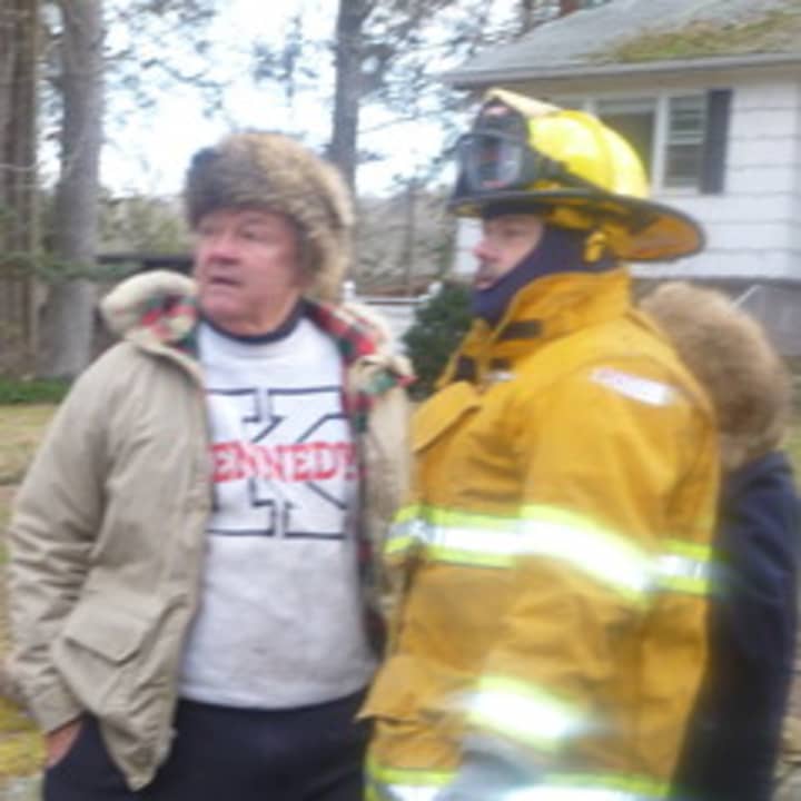 School Board Trustee Dr. Peter Treyz talks to a firefighter as he watches his South Salem home burn.