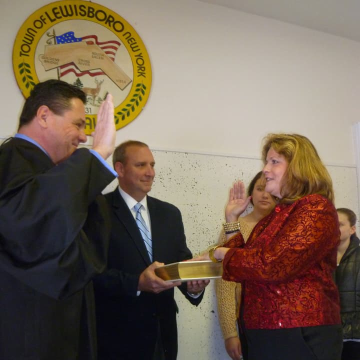 Janet Donohue, right, is sworn in by Lewisboro Town Justice Marc Seedorf. Her husband, Ken, holds the Bible while her daughters Jenna and Lauren look on.