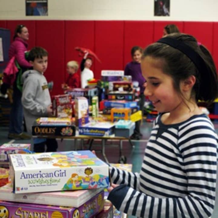 Fifth-grader Isabel Trinkaus helps her teachers set up for the tag sale at Scoland Elementary School in Ridgefield. She said looks forward to being a pen pal with a student at P.S. 104.