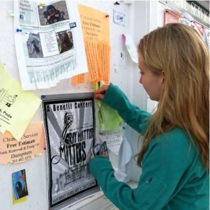 Clare Murray hangs a poster at Peter&#x27;s Market in Weston to promote the benefit concert she planned.