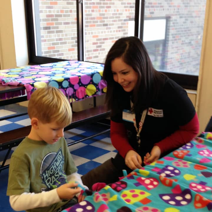 Red Cross Youth Services Associate Carissa Duro works on a comfort kit with a Primrose School student.