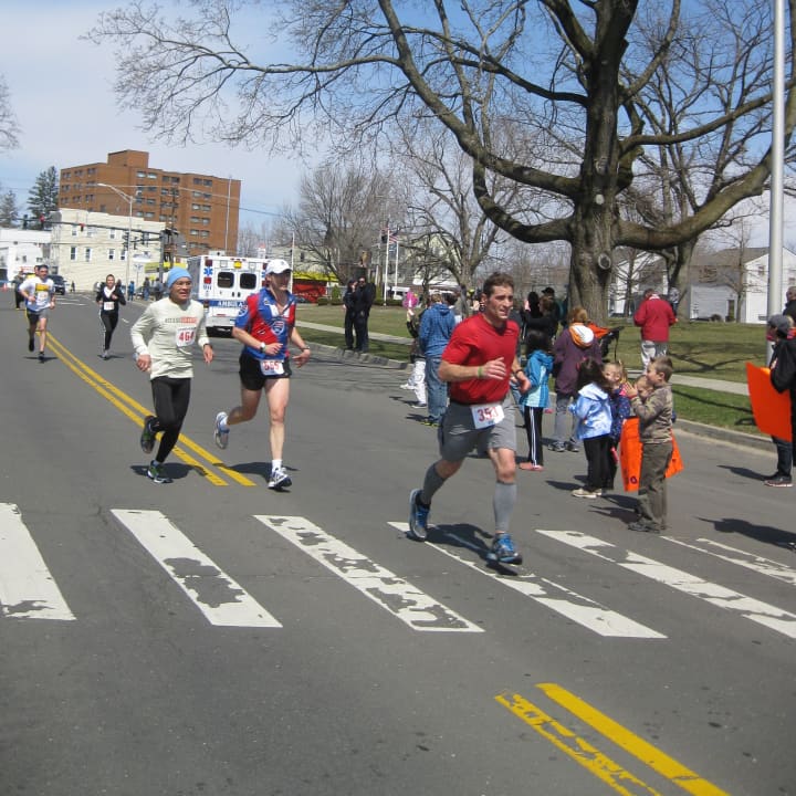 <p>A crowd of runners approaches the finish line in the Danbury Half Marathon.</p>