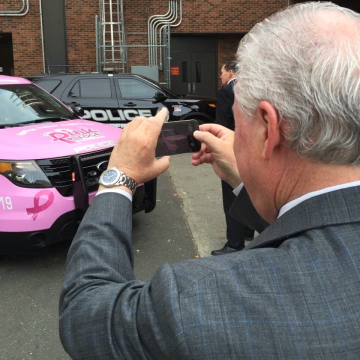First Selectman Michael Tetreau snaps a photo of the pink police cruiser following its unveiling Monday.