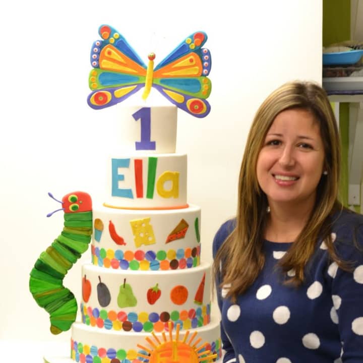 Renata Papadopoulos, owner of Lovely Cakes in Stratford, stands by a masterpiece cake she created for a child&#x27;s first birthday. 