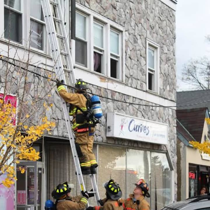 Firefighters climb to the apartments above two businesses where smoke and flames were located.