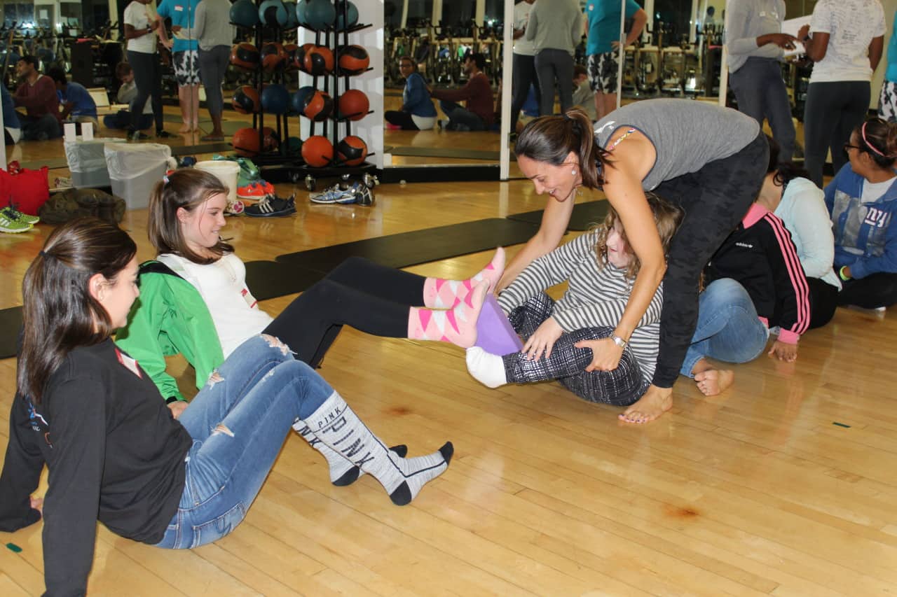 Participants in a yoga class for children with special needs at the Darien YMCA perform a “pass the block” exercise. Left to right: Shea Canaday (volunteer), Melissa Hartunian (volunteer), Sarah Dorris and Talita Moss (yoga instructor). 