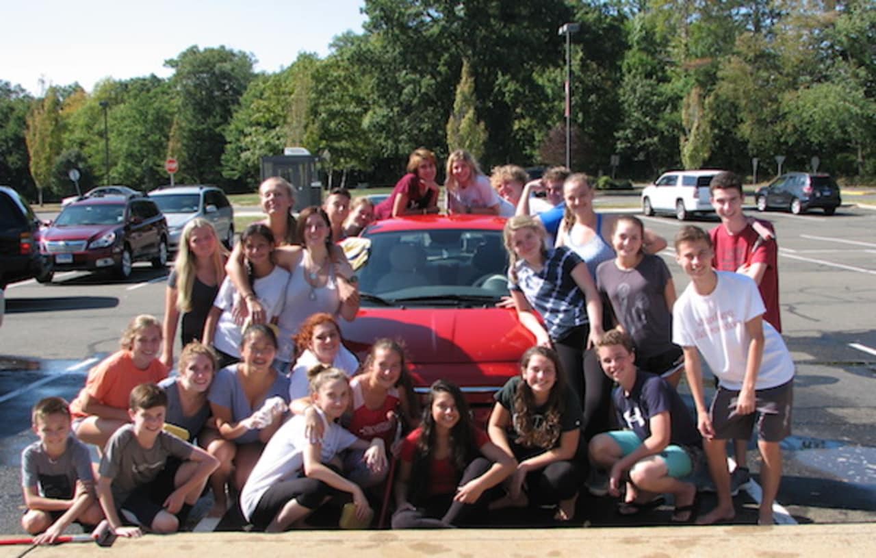 The New Canaan High School Theatre Department celebrates a successful car wash fundraiser.