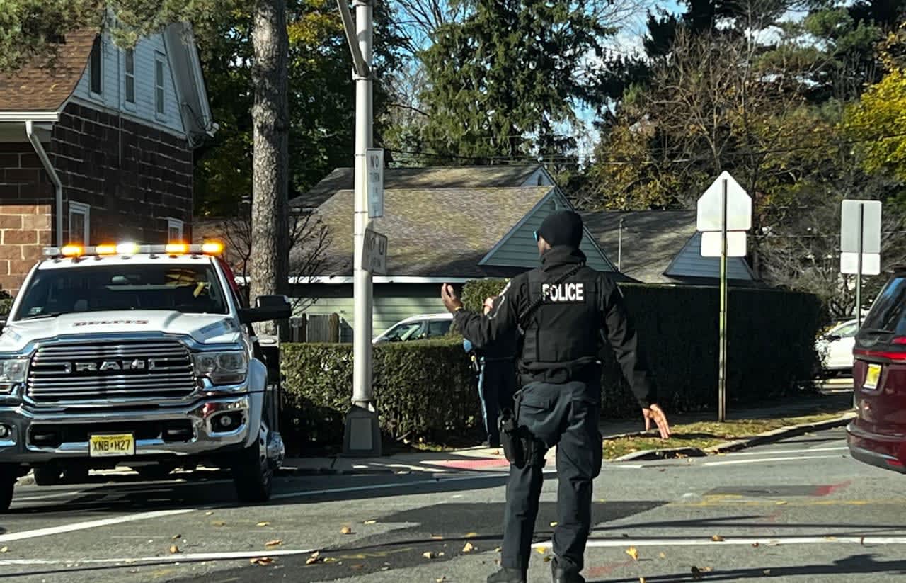 A tow truck removes the Jeep from the property of  the Romeyn-Oldis-Brinkerhoff House as one of the heroes, Maywood Police Officer Keion Best, directs traffic.