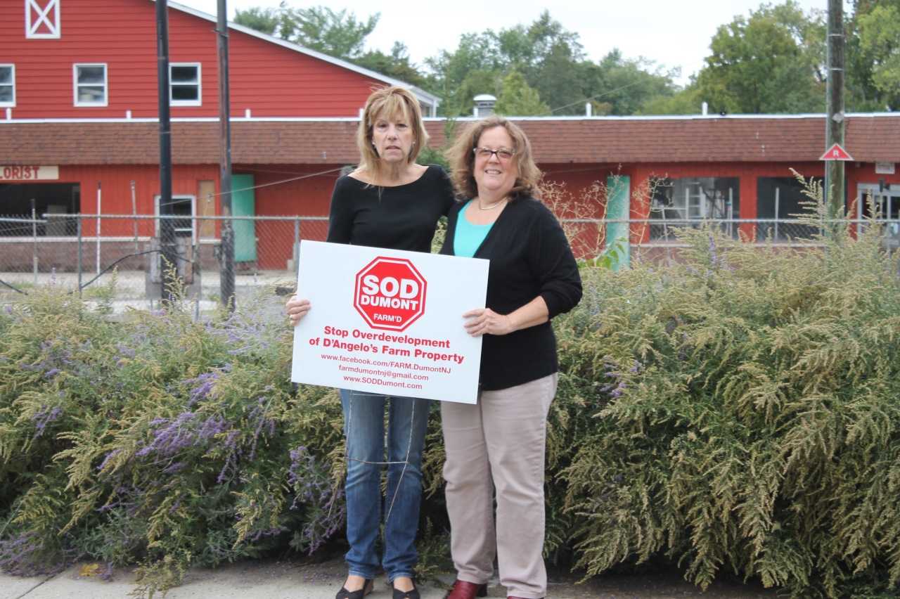 Lili Binney and Rachel Bunin hold their sign in front of D'Angelo Farm, which will be developed.