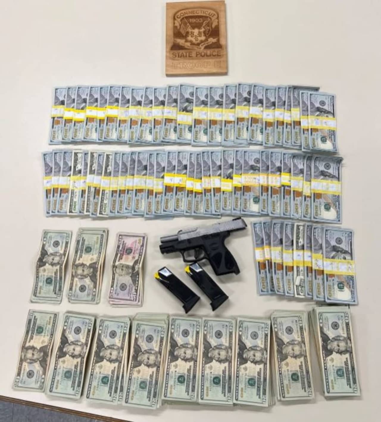A wanted man was taken into custody after police said he was pulled over while driving a tractor-trailer in Waterford that contained a loaded pistol and $70,000 in cash.