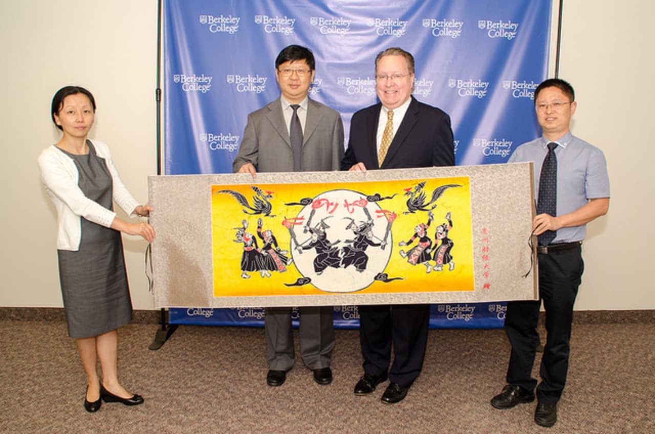 Yvonne Zhang, Chu Guangrong and Zhao Pu, of Guizhou University in China present this handmade gift to Berkeley College President Michael J. Smith, third from left.
