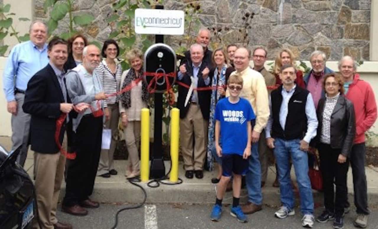 Fairfield First Selectman Michael Tetreau (back row, fifth from left) shows off one of the Town of Fairfield's electric vehicle charging stations at Fairfield Woods Library. Fairfield has encouraged electric vehicles in recent years.