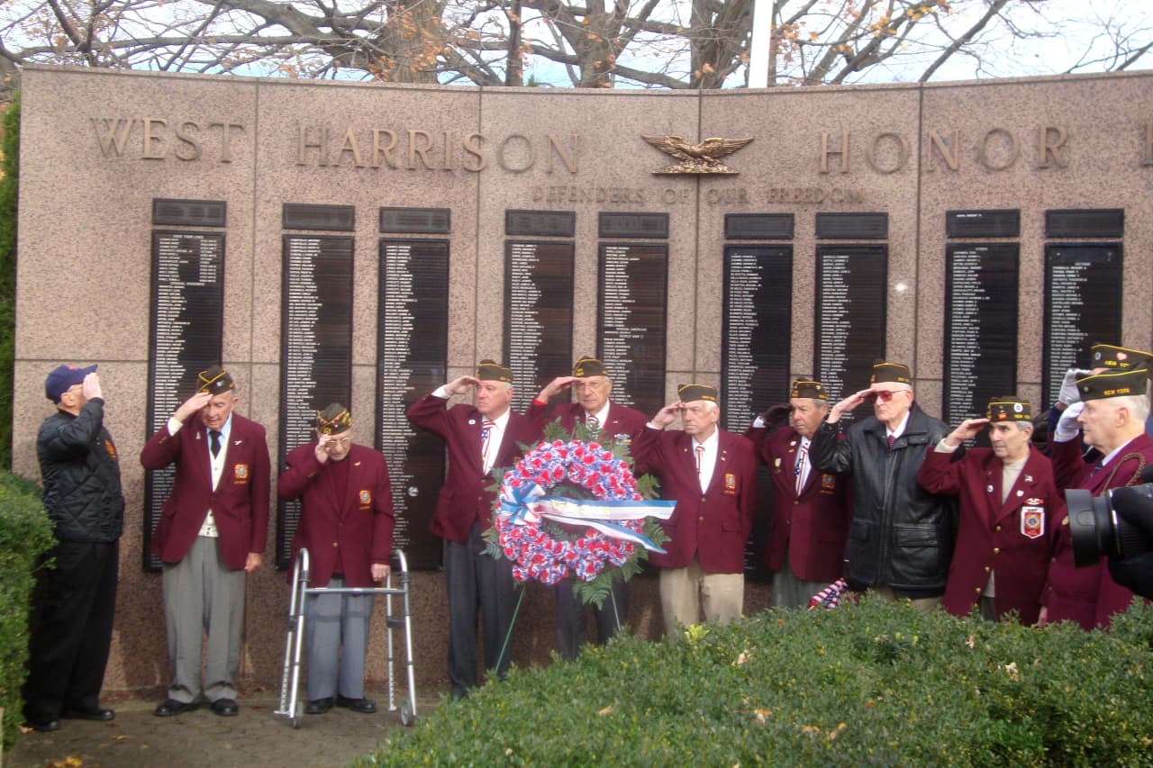 Veterans salute during Taps at the ceremony held on the West Harrison Village Green following the Veterans Day parade.