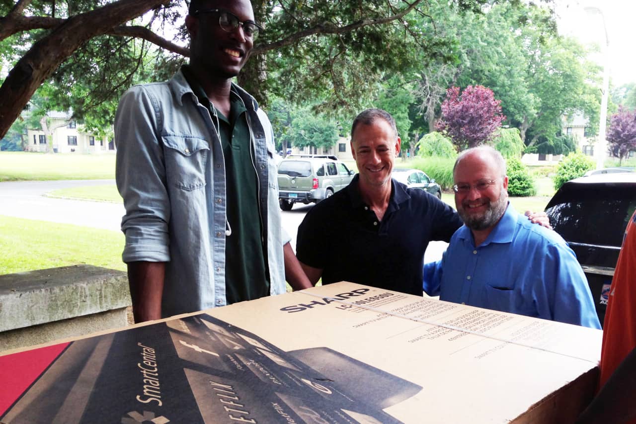 Dwight Thomas, Pleasantville Cottage School recreation staffer, Gregg Hammerschlag (who originally donated the TV to UJA-Federation to be used as the events grand prize), and David Perlmutter transport a tv to Pleasantville Cottage School.