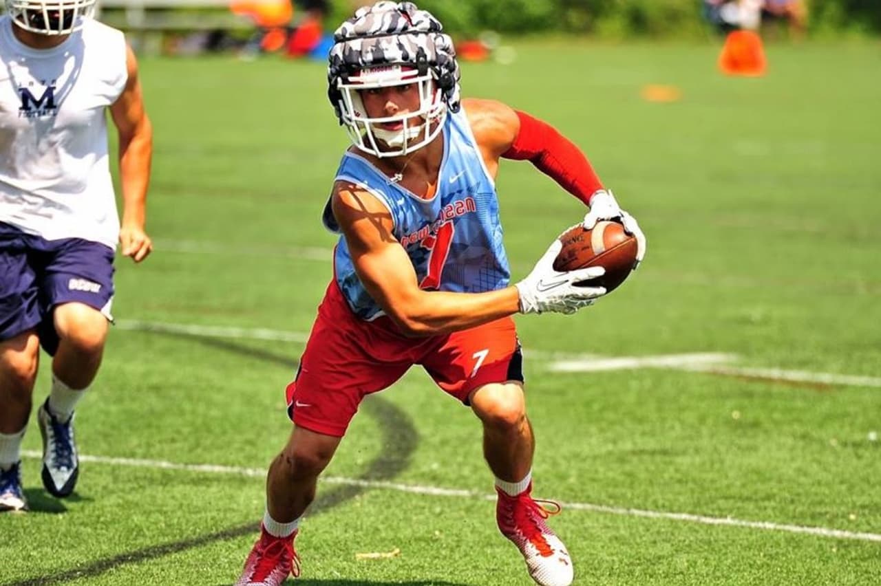 A New Canaan football player runs with the ball during a summer tournament.