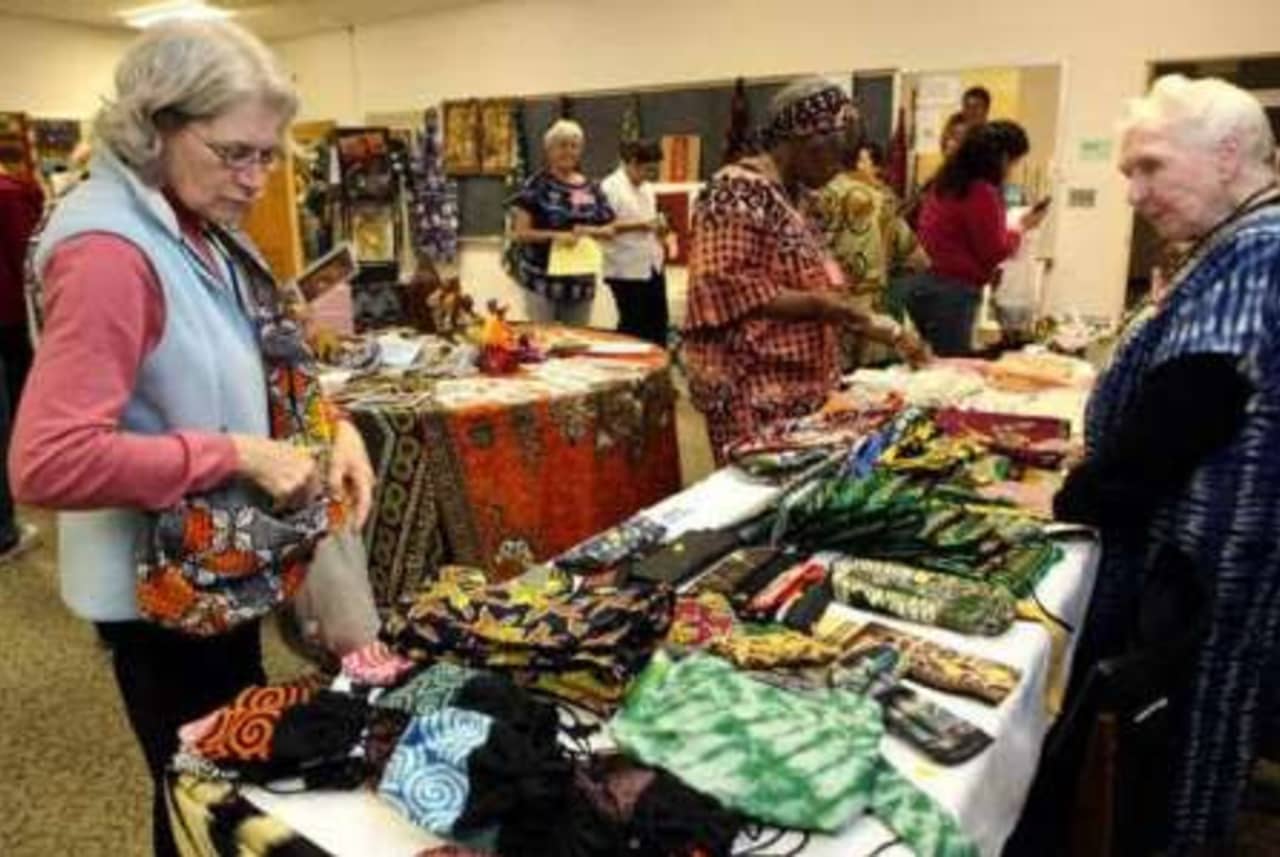 Woman examines some of the African handicrafts for sale at the 2013 bazaar. Tending the booth is Sister Marian Teresa Dury, who was a nurse in Tanzania for 24 years.