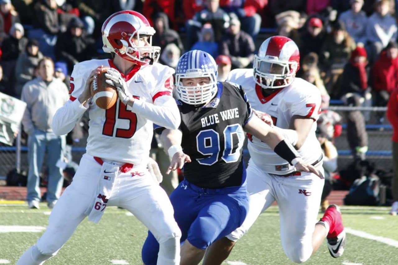 New Canaan quarterback Michael Collins looks for a receiver under pressure from Darien's Mark Evanchick.