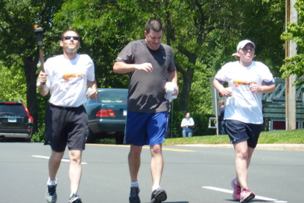 Westport Police Officer David Wolfe, left, runs with the Special Olympics "Flame of Hope" torch in a previous year.