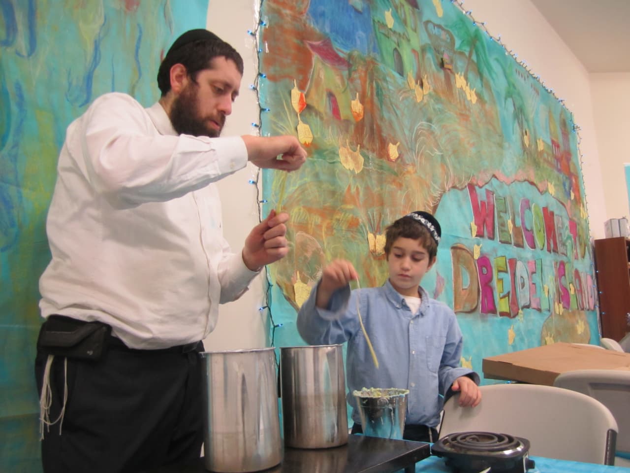 Rabbi Dovid Labkowski and son Menachemn make candles at Chabad at Briarcliff's "Dreidel Island" in Ossining.