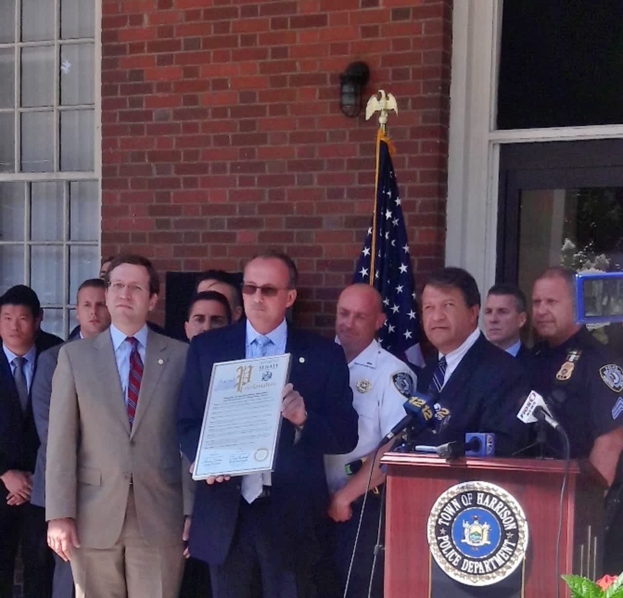 Harrison Police Chief Anthony Marraccini, holding proclamation, flanked by Assemblyman David Buchwald, left, and State Sen. George Latimer, right.