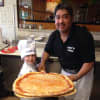A young chef takes a pizza out of the oven at Tony's Pizza in Pompton Lakes.