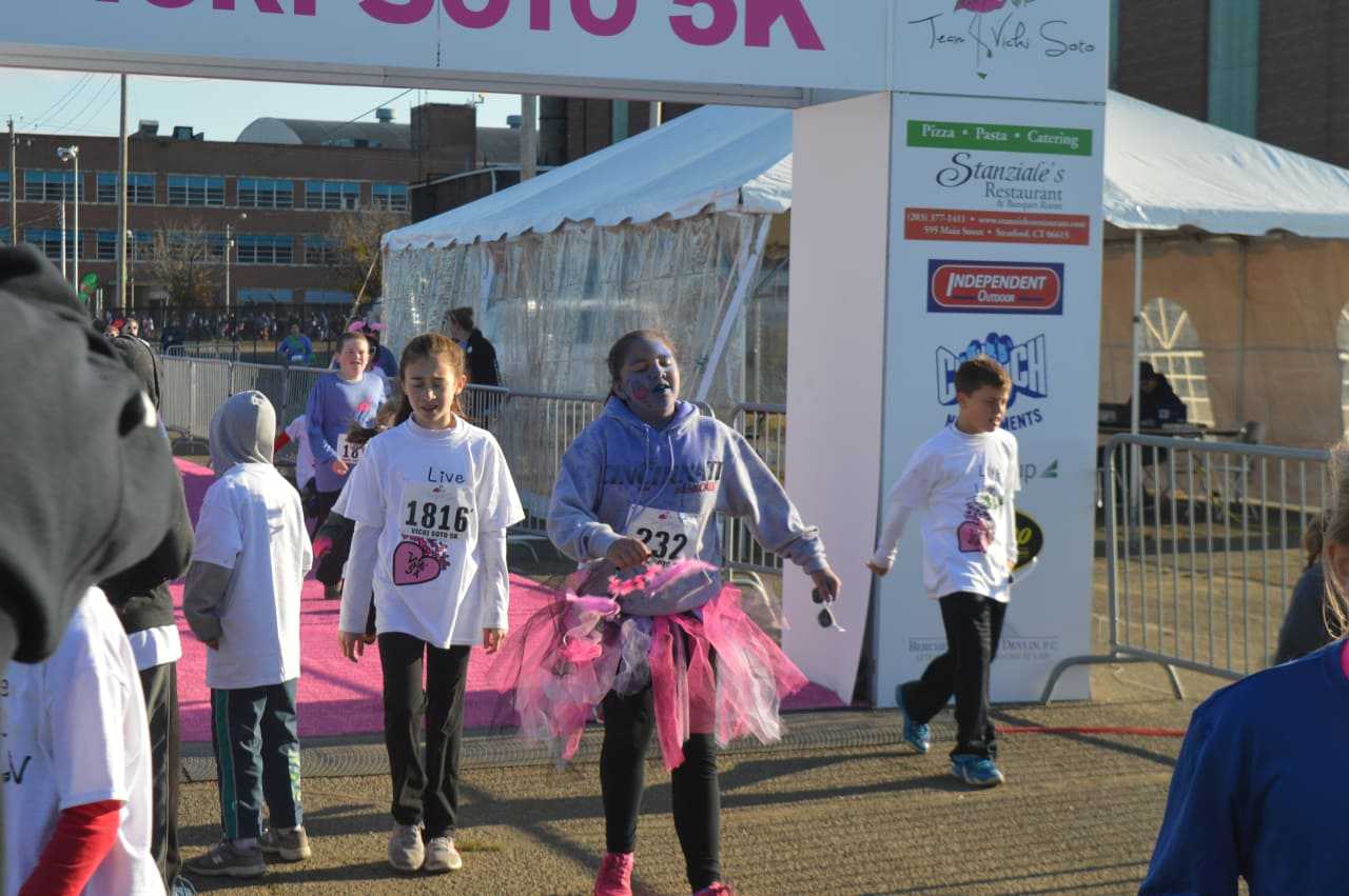 Participants in the kids fun run cross the finish line before the start of the 2016 Vicki Soto 5K in Stratford.