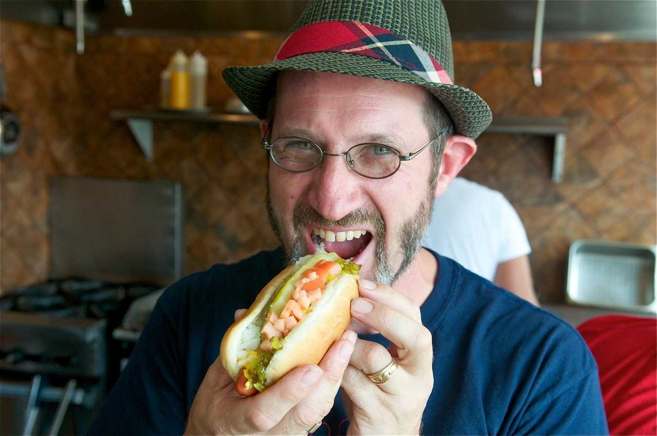 Noshi's owner Peter Newman takes a bite out of one of his trademark hot dogs.
