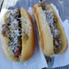 Hot dogs topped with fresh rosemary, raspberry, and caramelized onion with gruyere cheese.