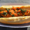 Hot dog topped with roasted pumpkin topping with parmesan cheese, sage, and roasted pepitas.