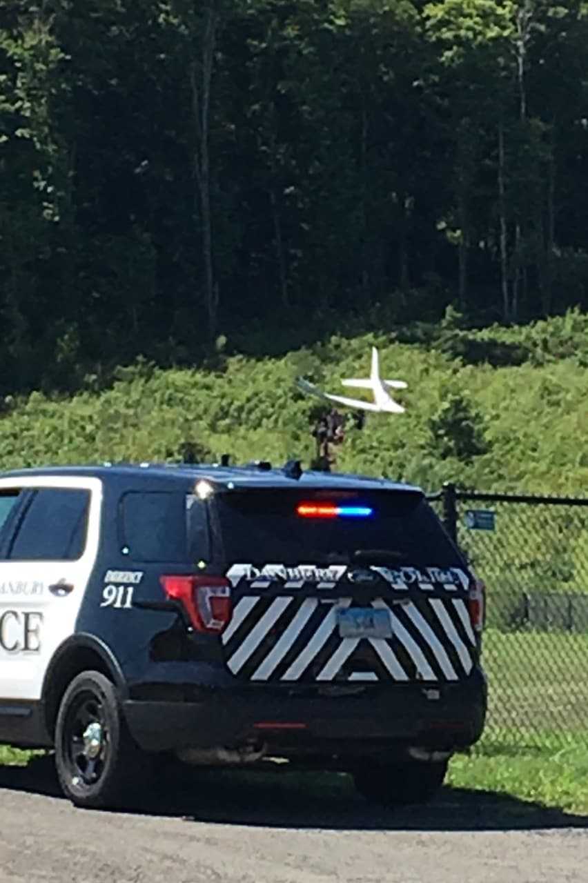 Crews walk up to the scene of plane crash on a hill above the dog park in Danbury on Sunday morning.