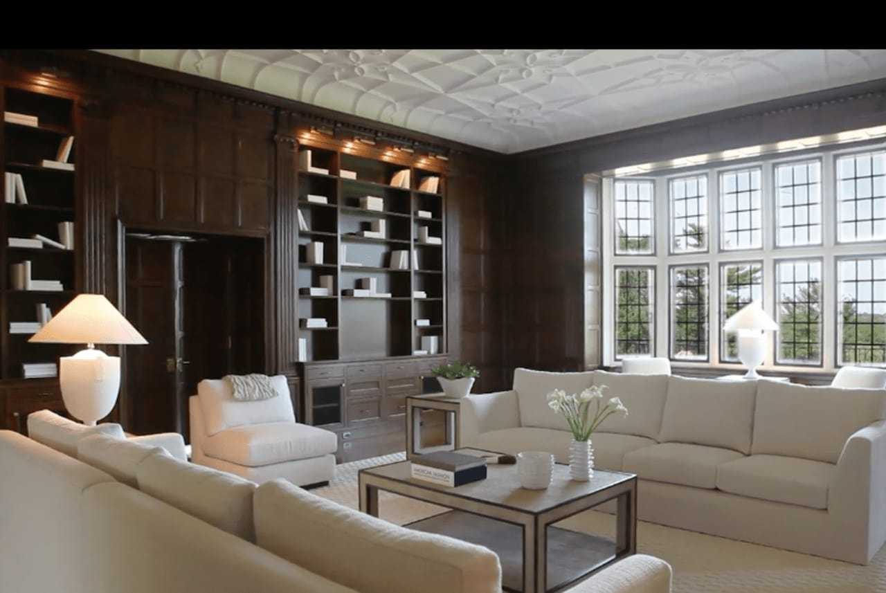 The library features lighted bookcases and a wall of windows.