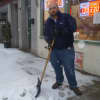 Firas Marji, a clerk at 24-hour Madaba Deli in Hastings, clears another snowfall from the sidewalk.