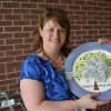 Lewisboro Elementary School Principal Cristy Harris holds up a plate that the school's PTA gave to her as a gift. The tree depicted on the plate included leaves made from students' fingerprints.