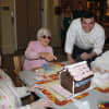 A volunteer from UBS assists women at Waveny LifeCare Network with building gingerbread houses.