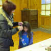 Local hairstylist Danielle Schepesi puts teal extensions into a girl's hair. 