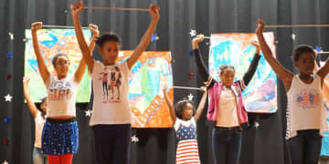Students raise batons during a performance Monday to mark Flag Day at Daniel Webster Elementary School.