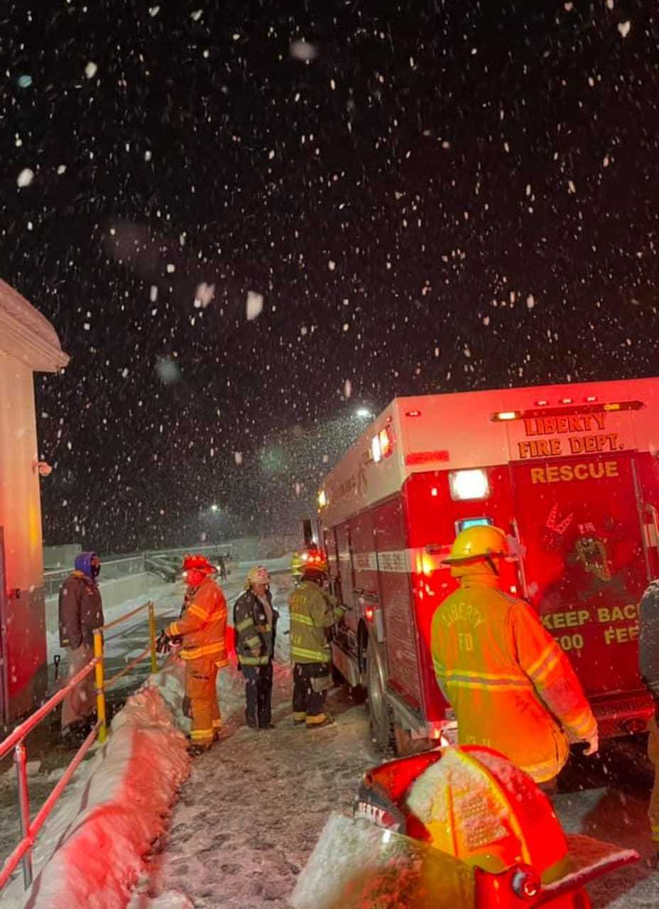 Liberty firefighters work to free a man whose hand had been pierced by an auger and pulled into a long pipe attached to a piece of machinery.