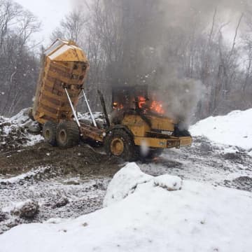 A dump truck working on a construction site caught fire after it tipped over to due slippery, snowy conditions.