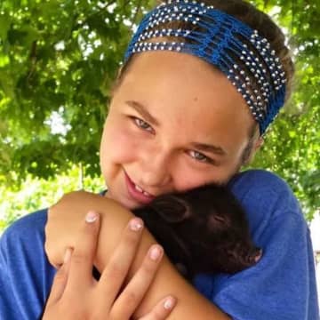 Tori Roberto with a three-week old pig at her West Milford home.
