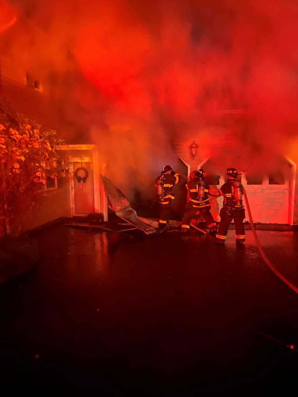 Norwalk firefighters working to keep a garage fire from spreading to the home.