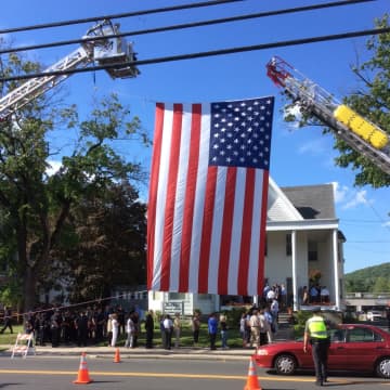 A U.S. flag hangs across the road at calling hours last Friday for retired police Lt. Kevin Kelly at the Bethel Funeral Home.