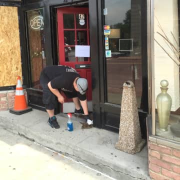 A man cleans up blood Monday afternoon at the Ink Side Out Tattoo shop on Wall Street in Norwalk.