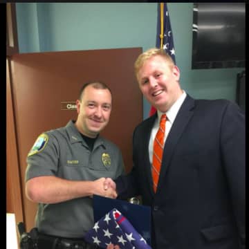 Newtown Police Department Officer Matthew Hayes was presented with a flag that was flown over the Nation's Capitol by Mackenzie Demac from Congresswoman Elizabeth Esty's office.