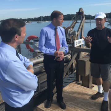 Commercial fisherman Ed Stilwagen explains clamming to U.S. Senators Chris Murphy, left, and Richard Blumenthal, center, at Greenwich Point on Friday.