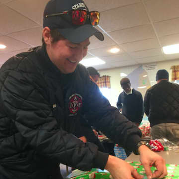 Stamford firefighter Eric Strain wrapping a present.