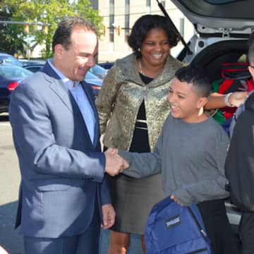Bridgeport Mayor Joe Ganim and Schools Superintendent Aresta Johnson present Juan Casiano of Puerto Rico with a new backpack as he gets ready to attend school in Bridgeport. New Canaan has also enrolled students from the hurricane-ravaged area.